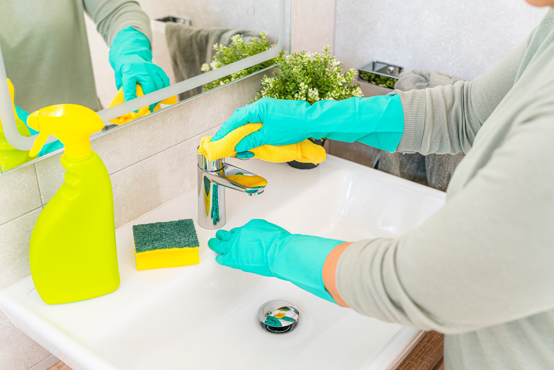 Woman polishing bathroom sink faucet with cloth